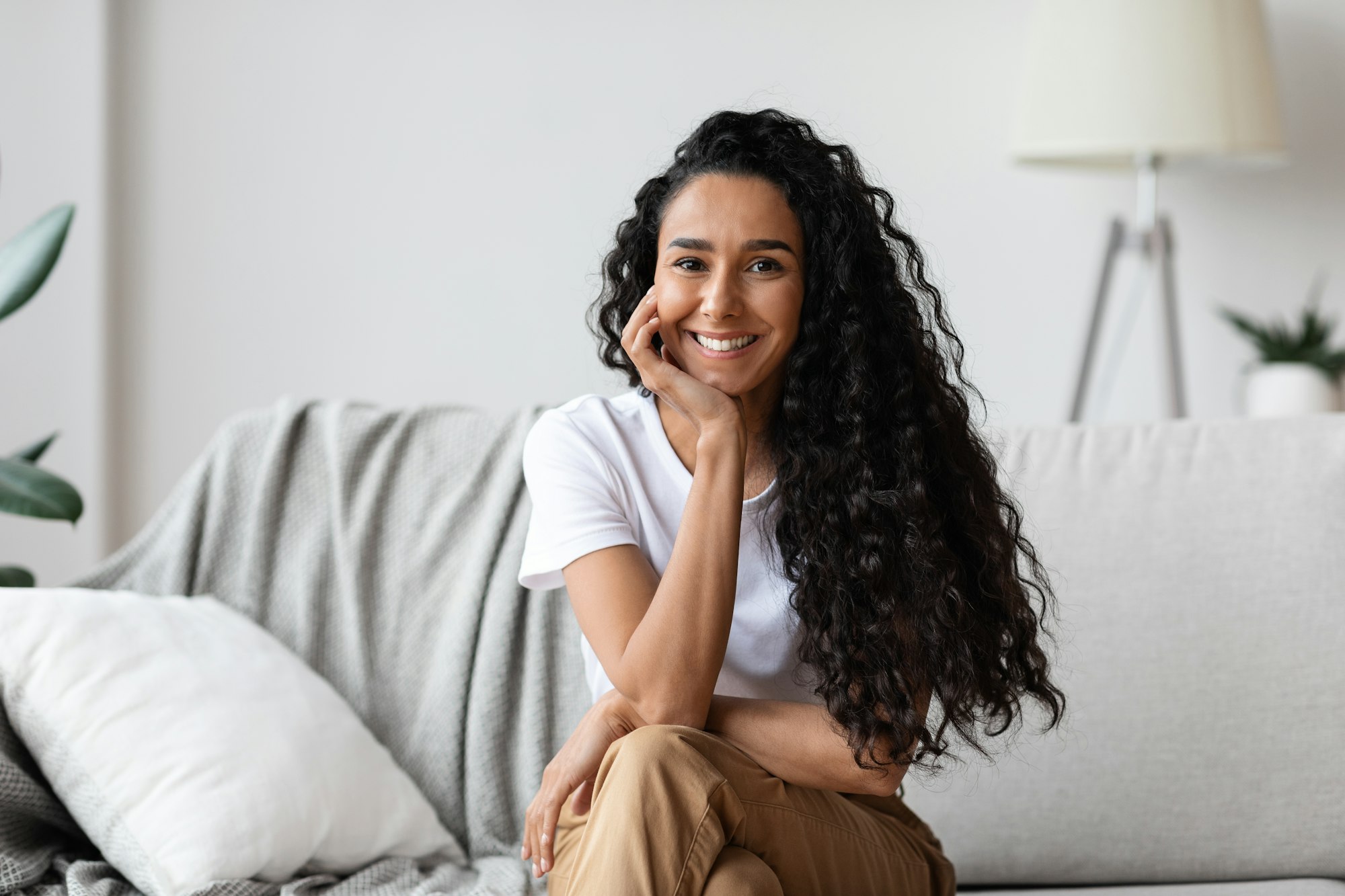 Potrait of happy millennial woman sitting on sofa at home